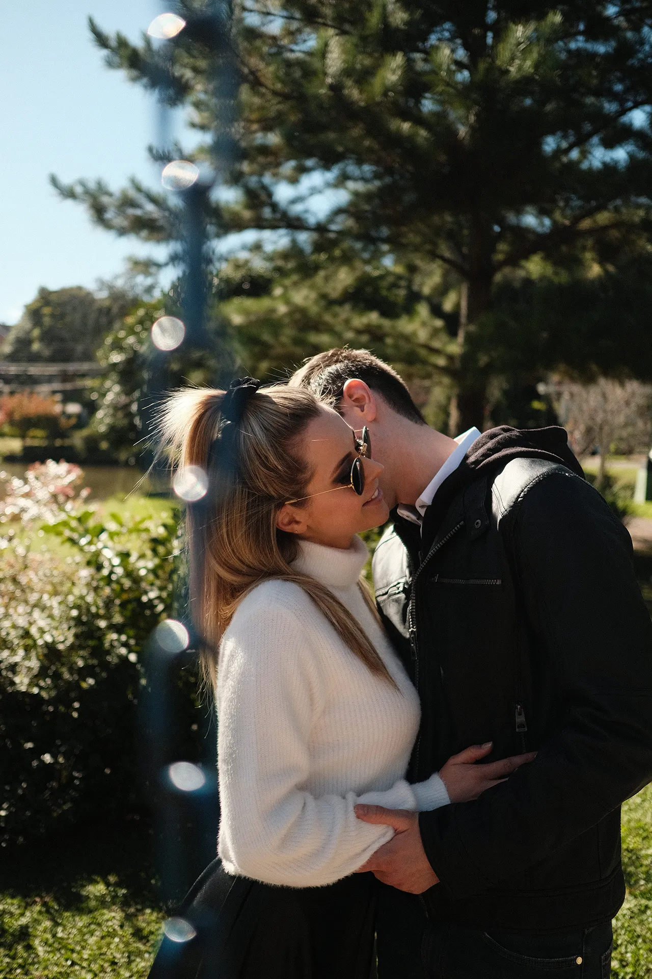 Casal se beijando entre luz e natureza
